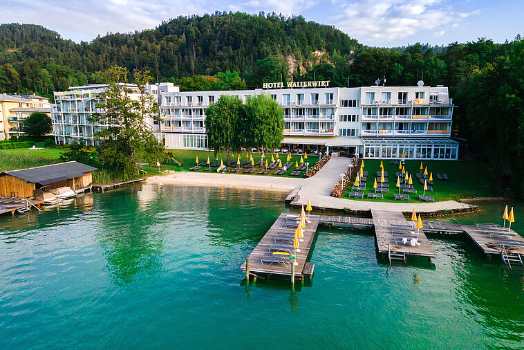 Blick über einen See mit Steg und Hotel im Hintergrund