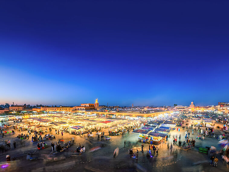 Nachtbildaufnahme eines beleuchteten Marktes in Marrakesch von oben