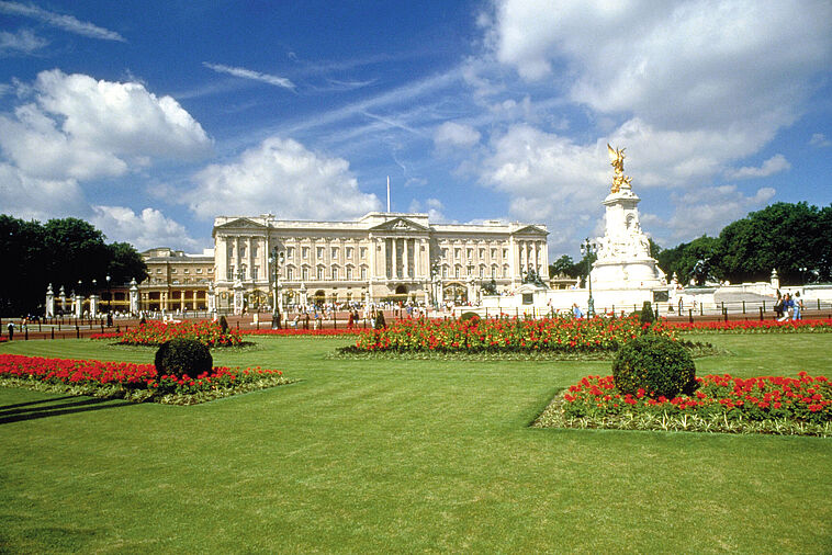 Blick über eine grüne Wiese auf den Buckingham Palace in London