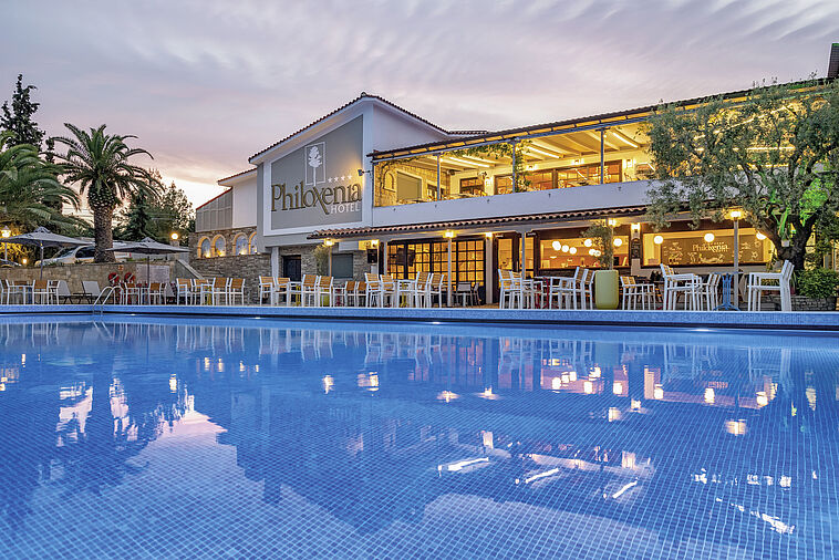 Blick über einen Pool auf ein Hotel in Abendstimmung